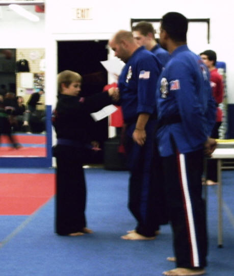 Zach receives his belt and certificate from the assembled instructors.