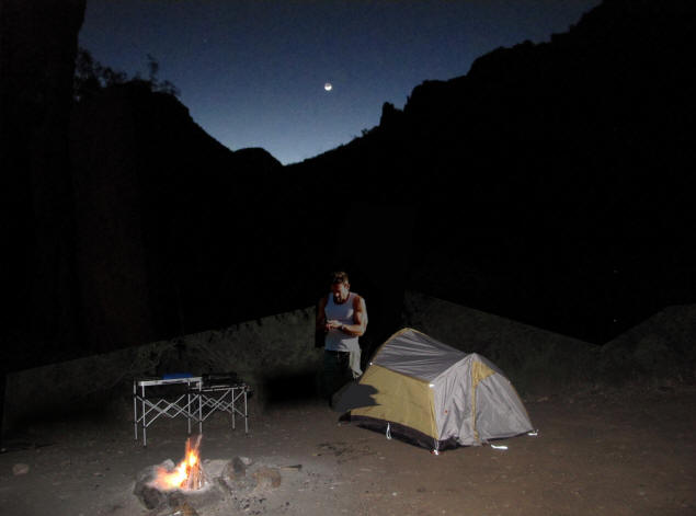 Frank at the tent beneath a setting, new moon.
